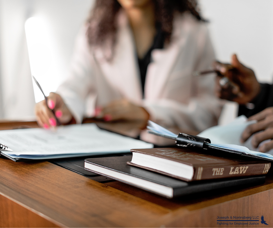 Two people signing paperwork with law books around them