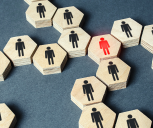 Wooden hexagonal blocks set end to end with a black figure painted on all except one with a red figure to depict gender discrimination