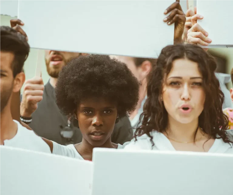 close up of a black woman and a white woman holding up signs at a protest against race discrimination