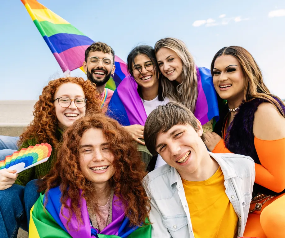 A group of LGBTQ+ individuals enjoying outdoor Pride month activities and flying a rainbow flag