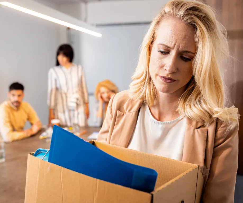 Woman leaving an office with a box of her belonging after being wrongfully terminated by her employer