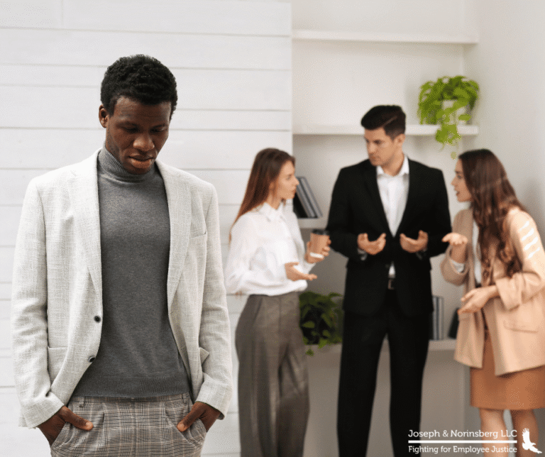 Employees in the background speaking to each other with another employee in the foreground looking sullen